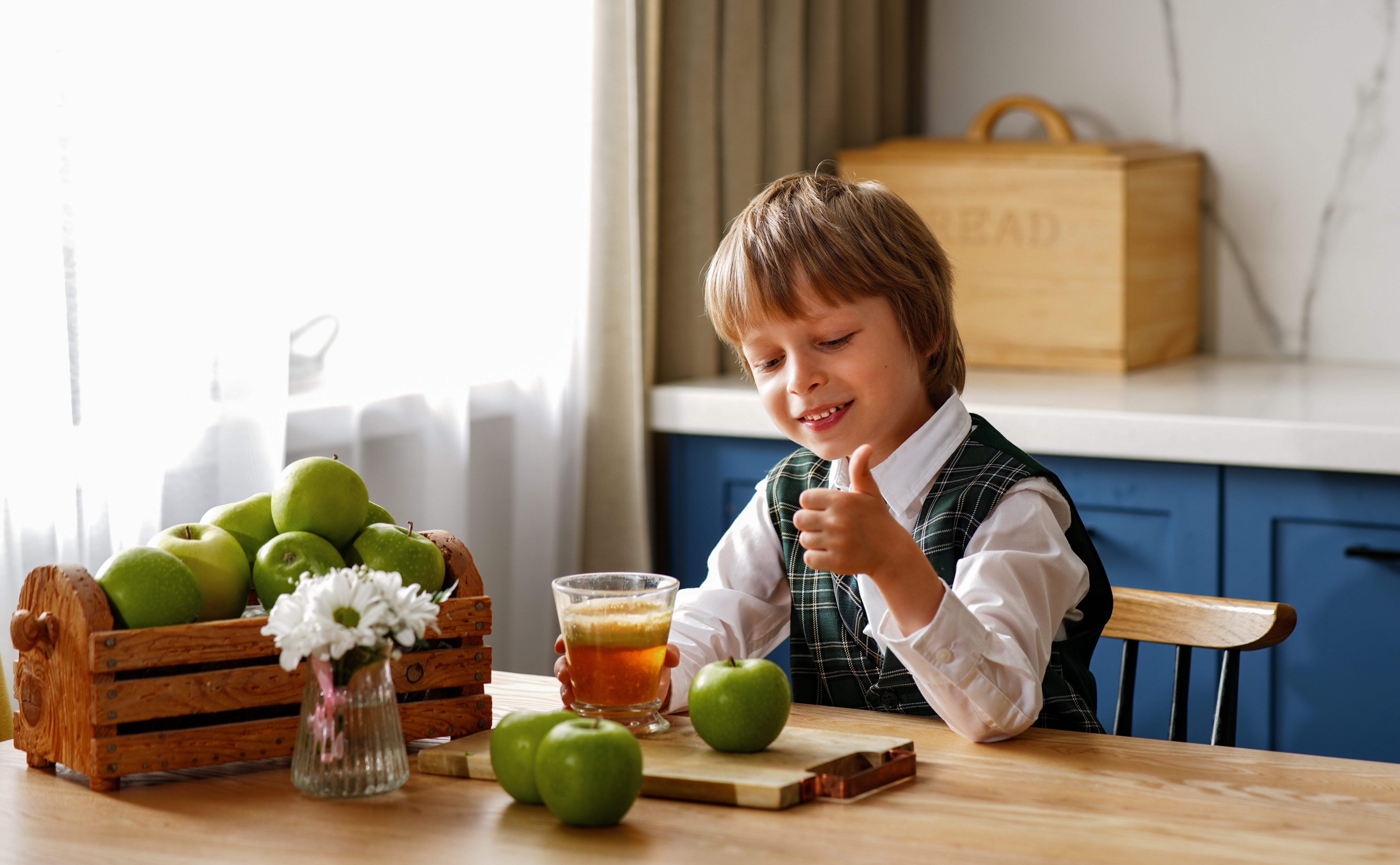 Smiling schoolboy drinks fresh apple juice for breakfast. Vitamins and healthy nutrition for kids
